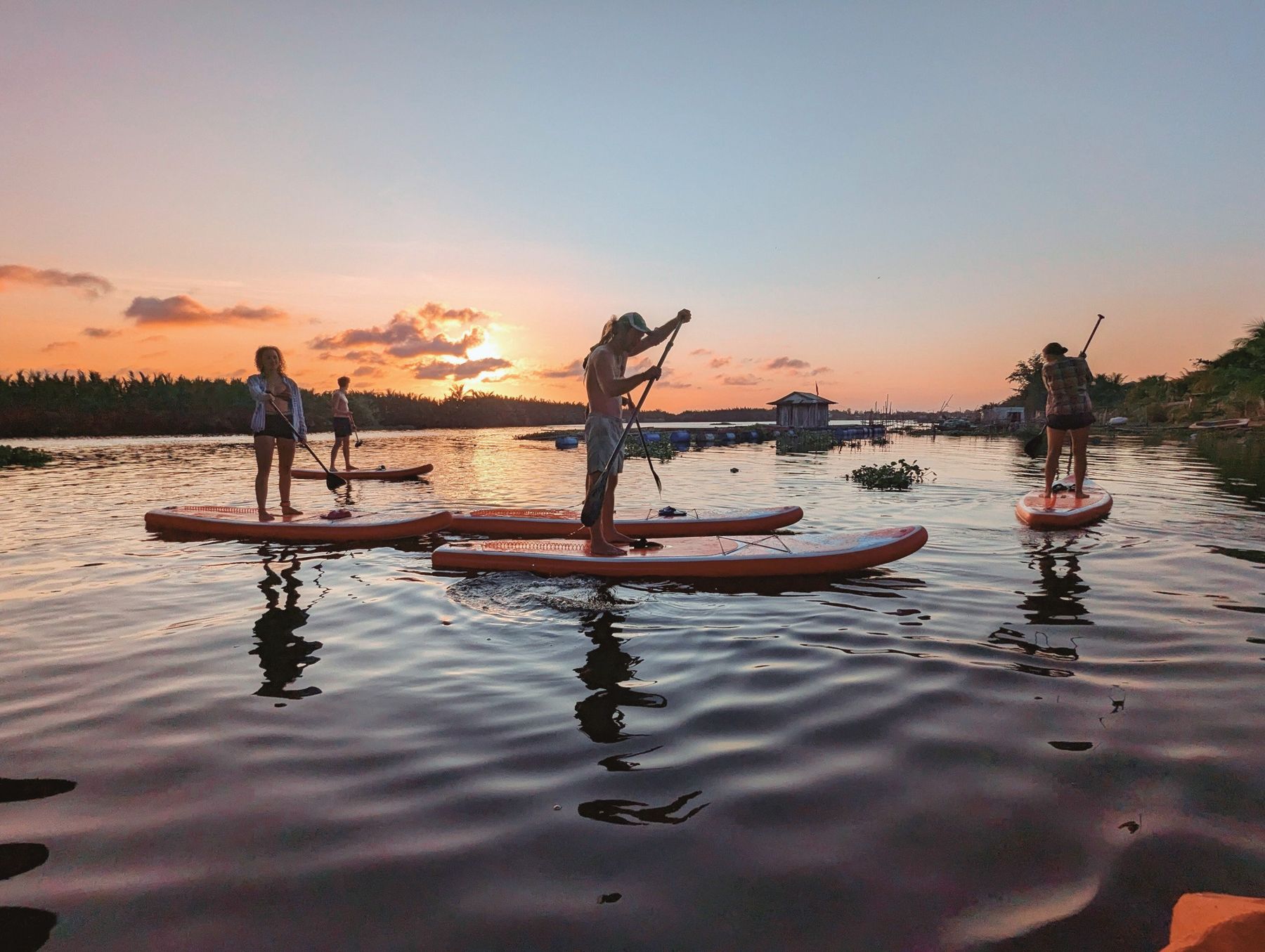Gruppe von Stand-up-Paddlern auf dem Fluss bei Hoi An im Sonnenuntergang